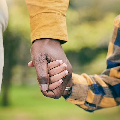 Close up of BAME man's hand holding a young boy's