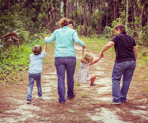 Man, woman and two small chilren holding hands in a line