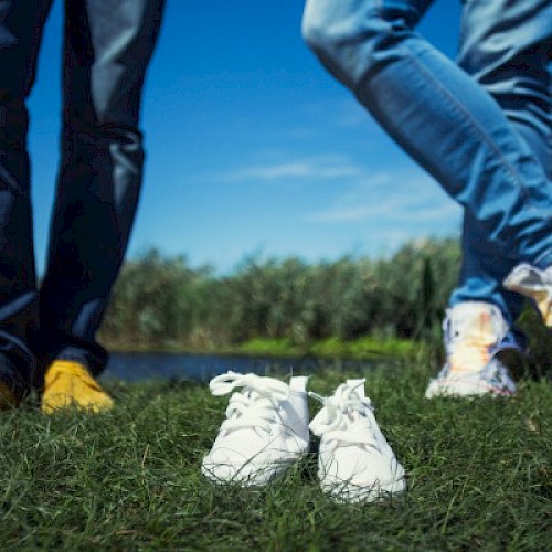 Small shoes inbetween to pairs of men's legs