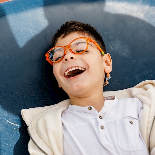 Special needs boy laying on the floro and laughing